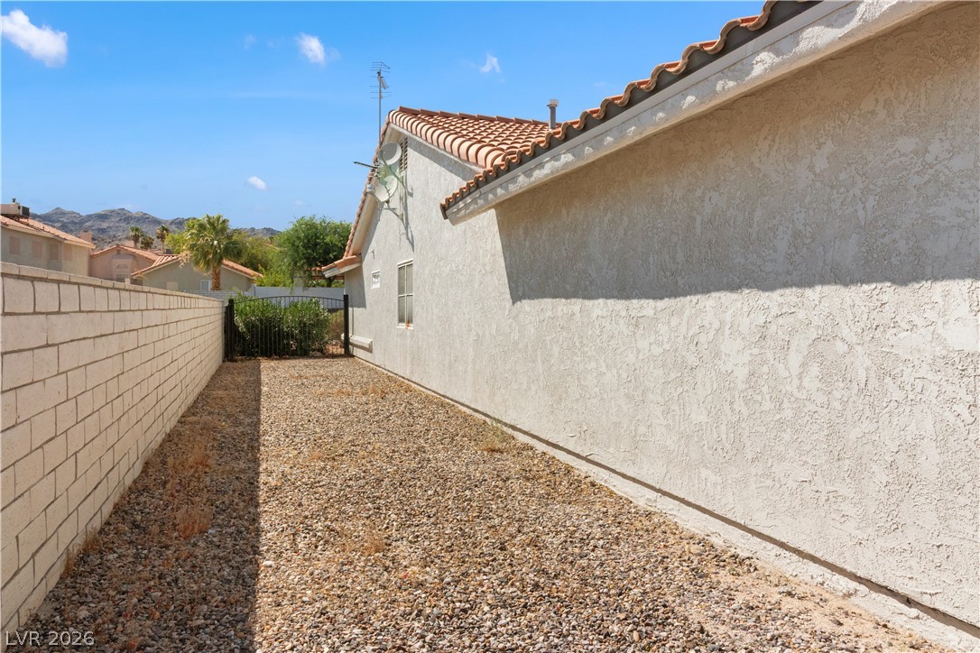 2055 Cholla Way Laughlin, NV 89029 - Photo 57 of 87 A side yard with gravel groundcover is bordered by a block fence and the home's stucco exterior.