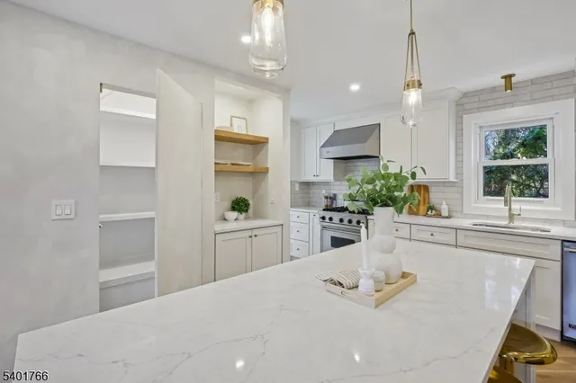 a kitchen with stainless steel appliances kitchen island granite countertop a white cabinets a sink and a stove