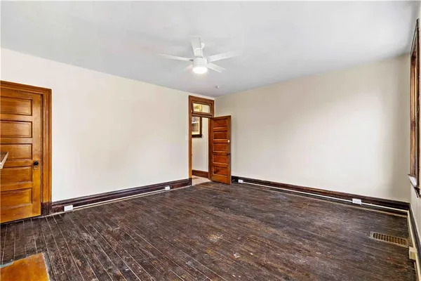 an empty room with wooden floor closet and windows