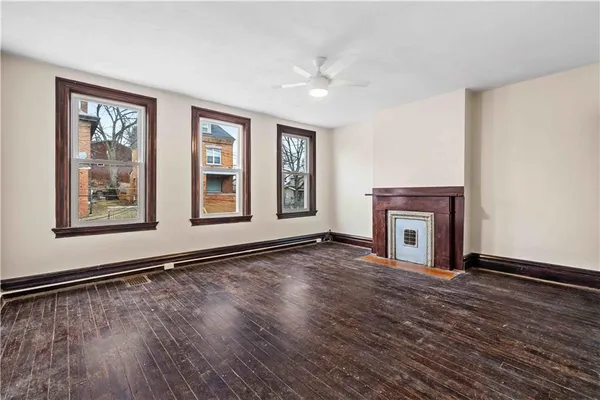 a view of an empty room with window and wooden floor