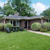 a view of a yard in front of a house with plants and large tree