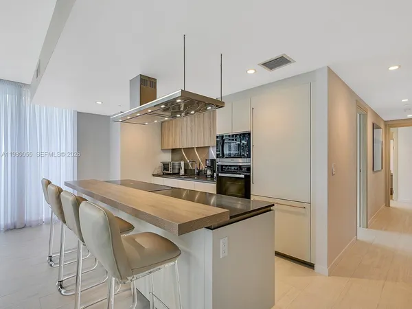 a kitchen with stainless steel appliances kitchen island a table chairs in it and wooden floors
