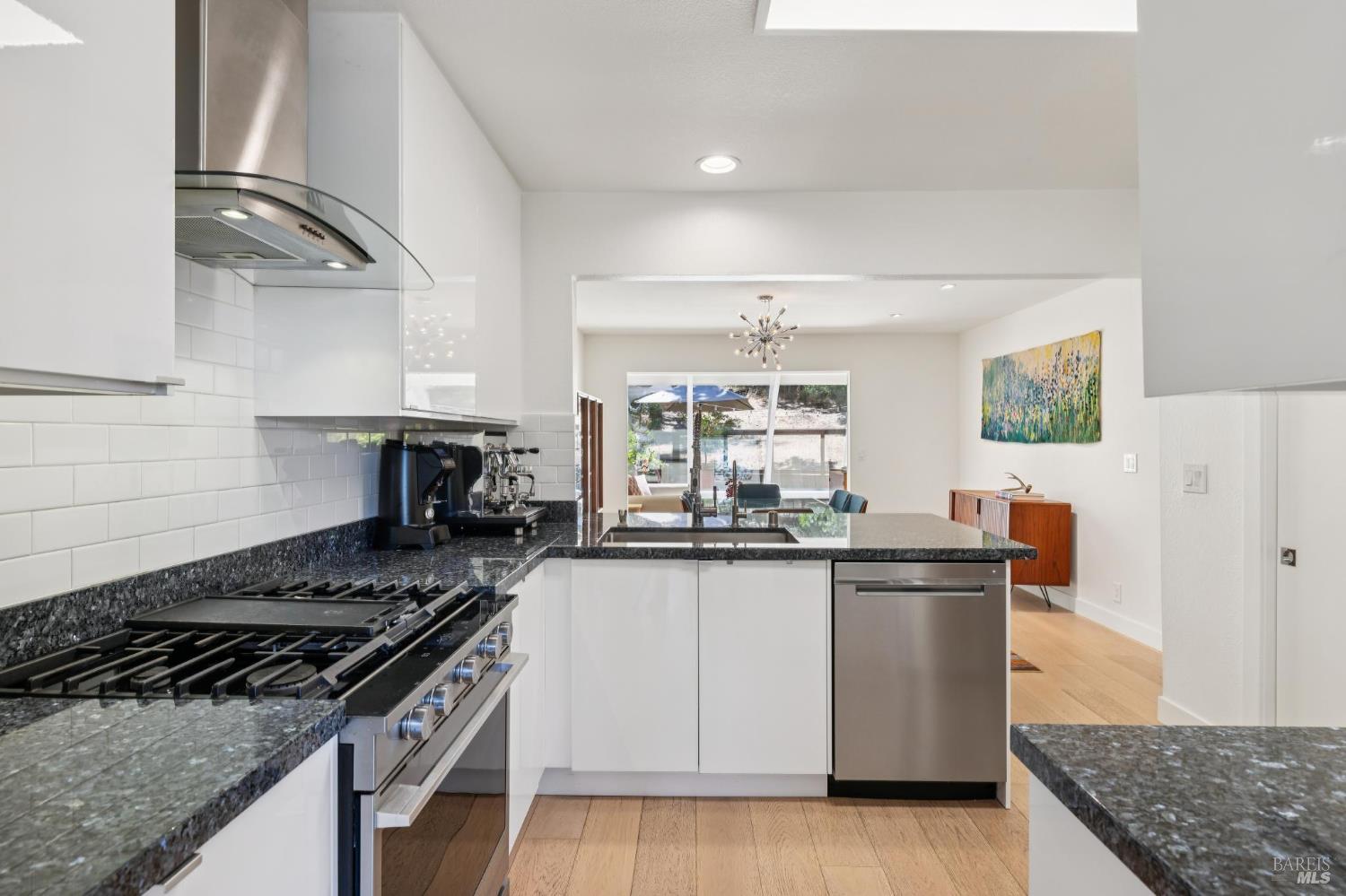 1045 Susan Way Novato, CA 94947 - Photo 21 of 62 Bright kitchen featuring white-gloss cabinets, a railroad-tile backsplash, granite countertops, and stainless-steel appliances.