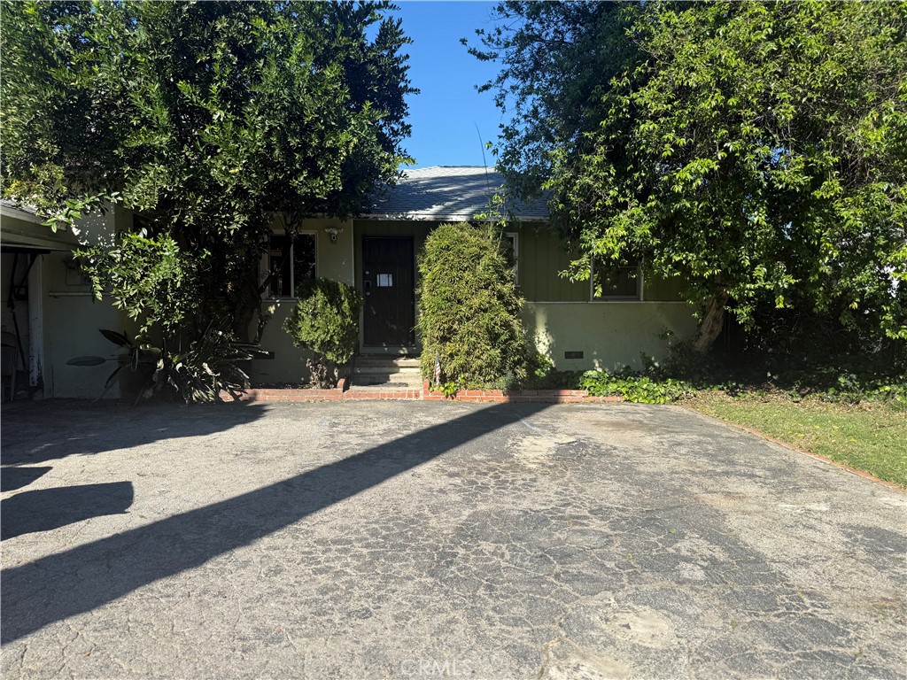 a view of a house with potted plants and large trees