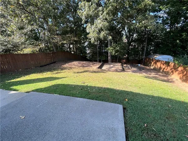 a view of a swimming pool with a yard and large trees