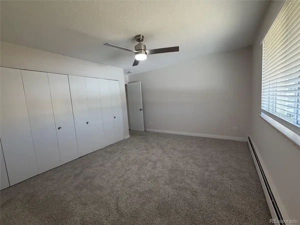 an empty room with a window and a fan