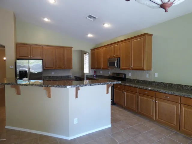 a kitchen with kitchen island granite countertop a sink stove and refrigerator