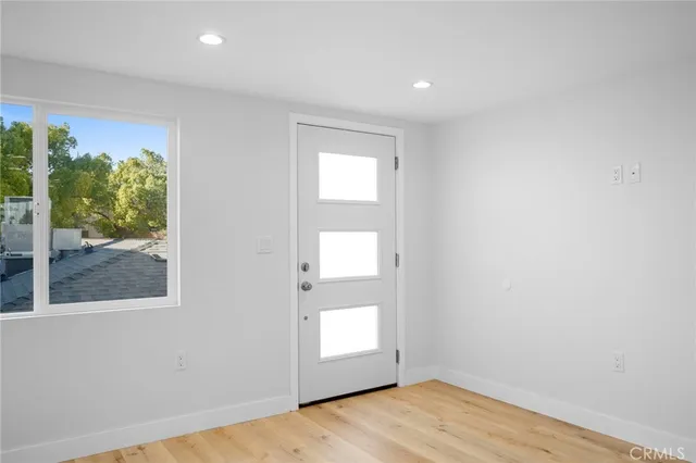 a view of an empty room with kitchen and window