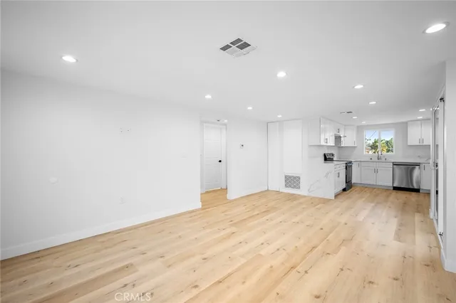 a view of an empty room with wooden floor and windows