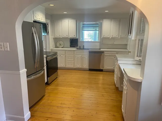 a kitchen with granite countertop a refrigerator a sink a stove top oven and cabinets