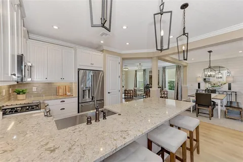 a large white kitchen with lots of counter space dining table and stainless steel appliances