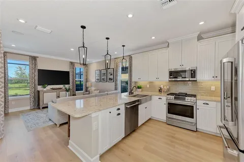a large white kitchen with stainless steel appliances granite countertop a stove and a sink