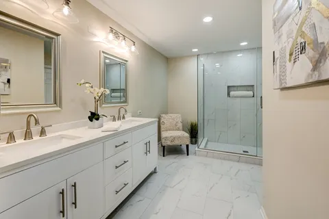 a spacious bathroom with a double vanity sink toilet mirror and shower