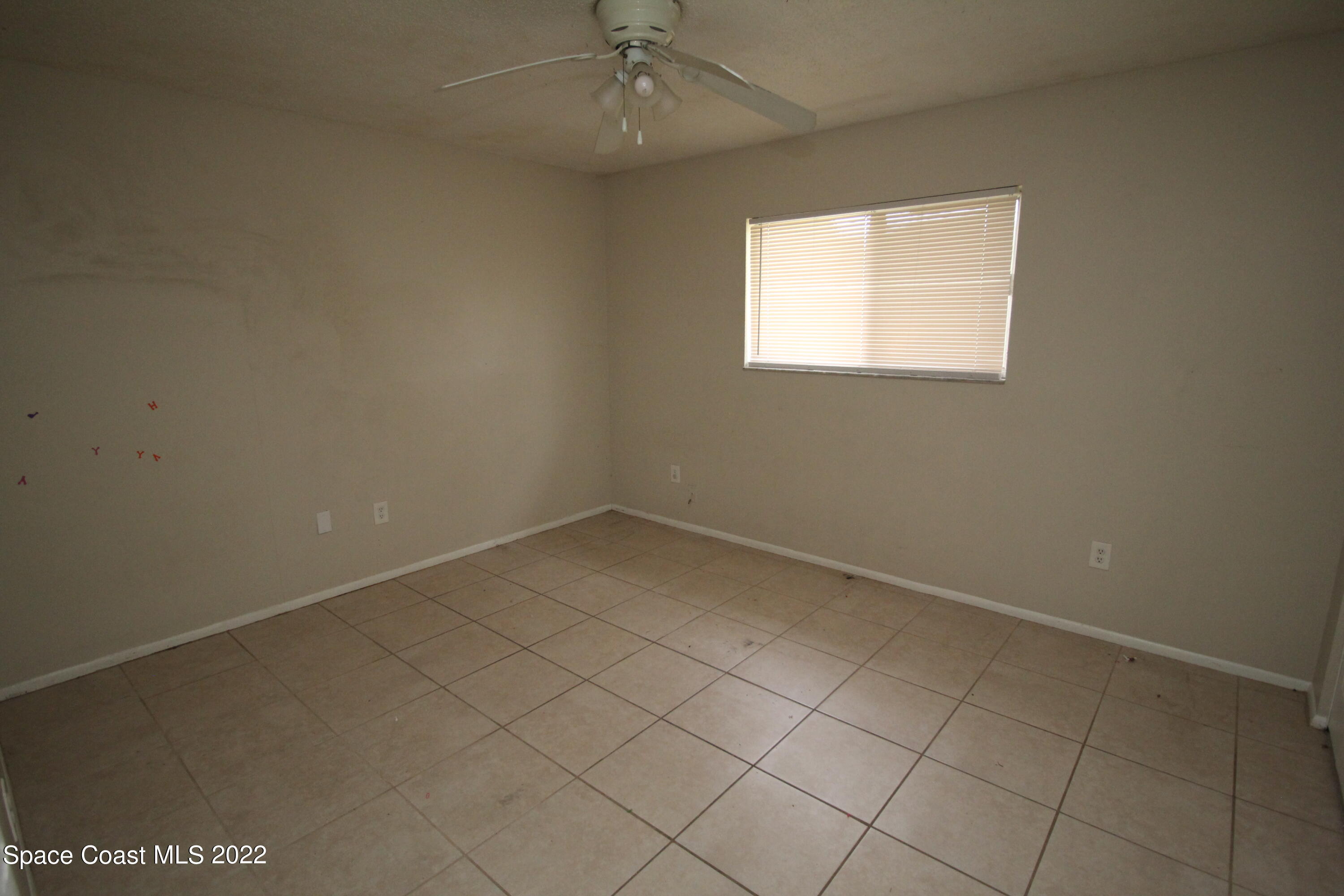 992 Sable Circle Southeast Palm Bay, FL 32909 - Photo 5 of 8 an empty room with a ceiling fan and window