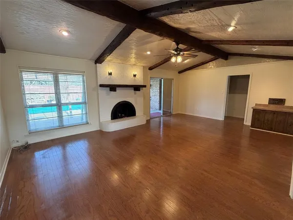 a view of an empty room with wooden floor and a fireplace