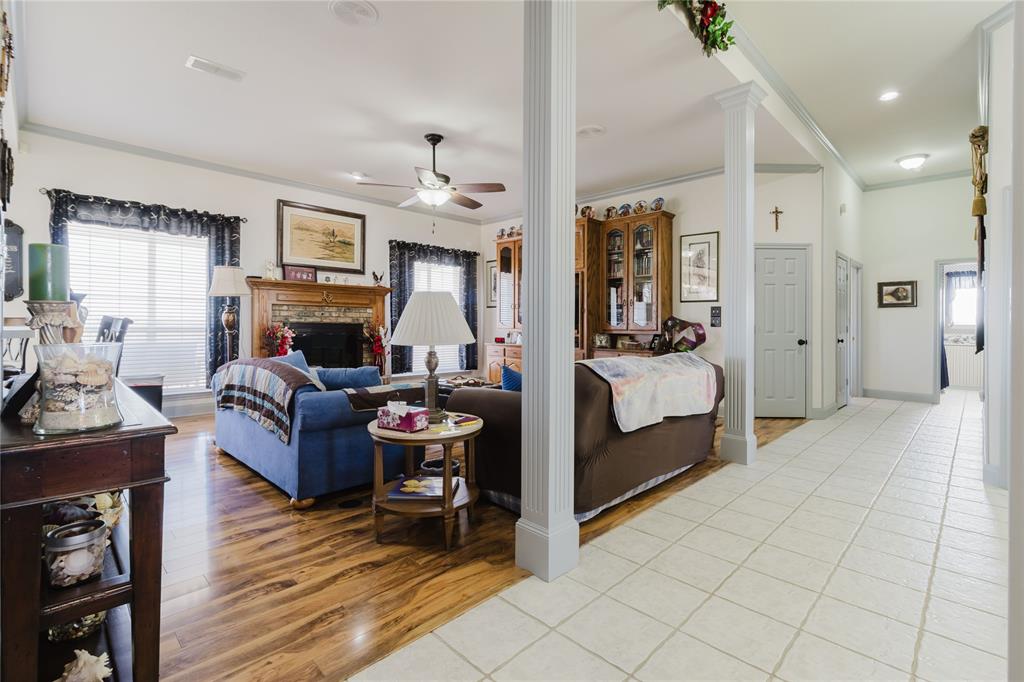 130 Blazek Road Alma, TX 75119 - Photo 11 of 30 Living room with ceiling fan, ornamental molding, light wood-type flooring, ornate columns, and a brick fireplace