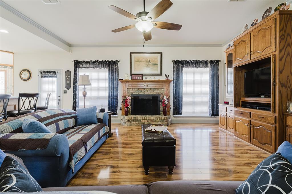 130 Blazek Road Alma, TX 75119 - Photo 14 of 30 Living room featuring a fireplace, ornamental molding, light hardwood / wood-style floors, and ceiling fan