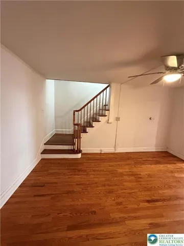a view of kitchen and empty room with wooden floor