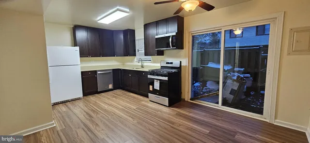 a kitchen with stainless steel appliances granite countertop a refrigerator a sink and a stove with wooden floors