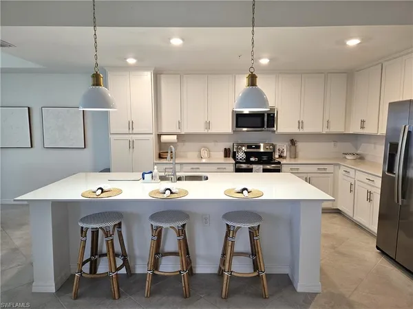 a kitchen with stainless steel appliances granite countertop a sink a stove a refrigerator cabinets and chairs