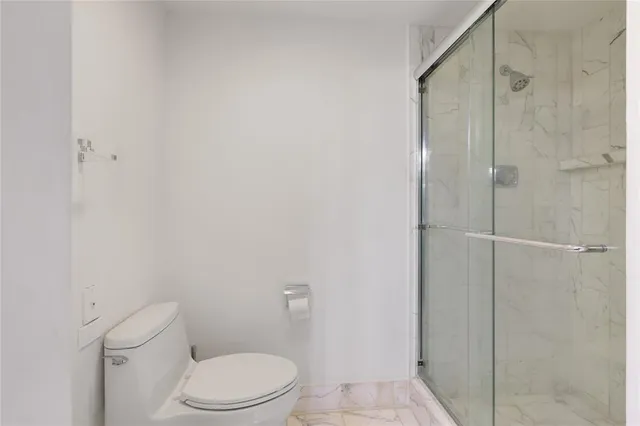 a white toilet sitting next to a shower