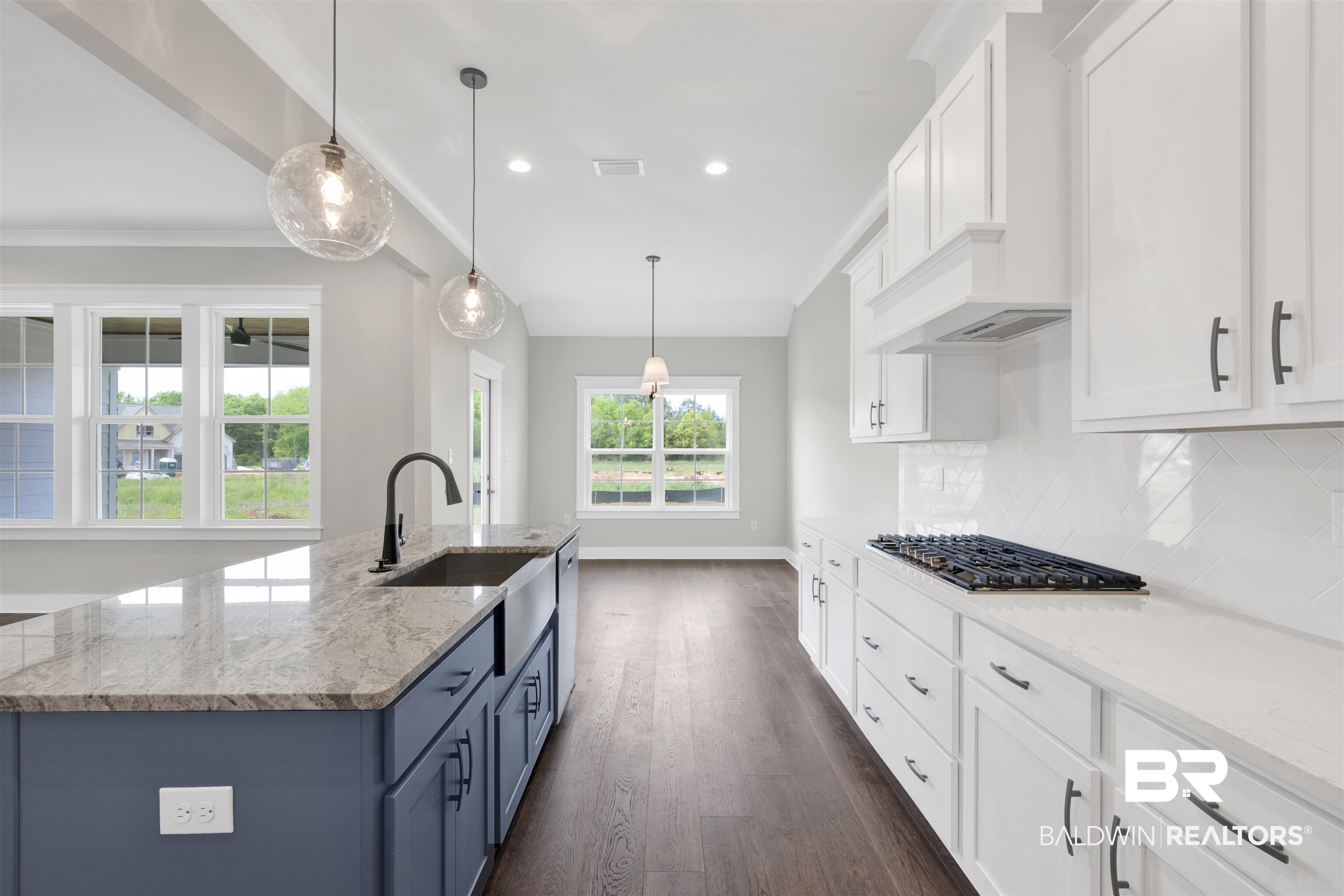27315 Patch Pl Loop Daphne, AL 36526 - Photo 13 of 43 Kitchen featuring dual tone cabinets, light stone countertops, decorative light fixtures, dark wood-type flooring, and an island with sink