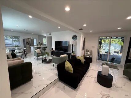 a living room with furniture kitchen view and a large window