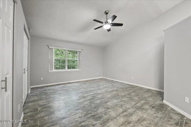 an empty room with windows and fan