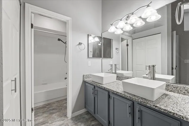 a bathroom with a granite countertop sink a large mirror and a shower