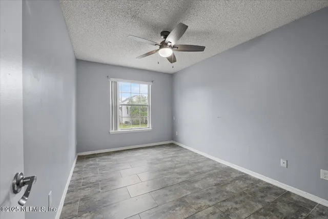 an empty room with windows and ceiling fan