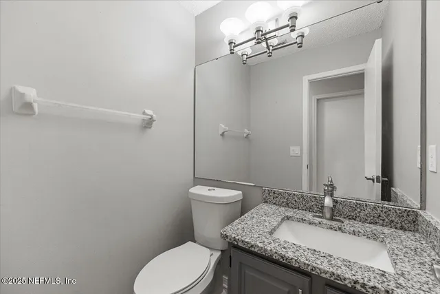 a bathroom with a granite countertop toilet a sink and a mirror