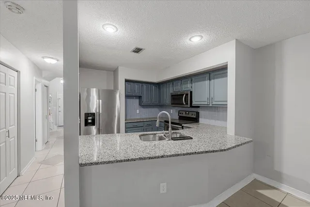 a kitchen with stainless steel appliances granite countertop a sink refrigerator and cabinets