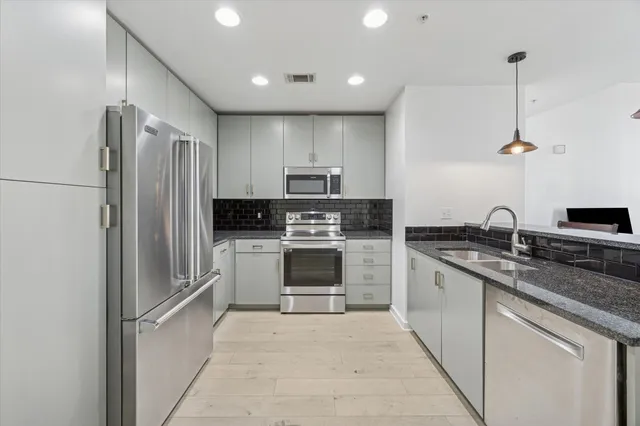 a kitchen with stainless steel appliances granite countertop a stove a sink and a refrigerator