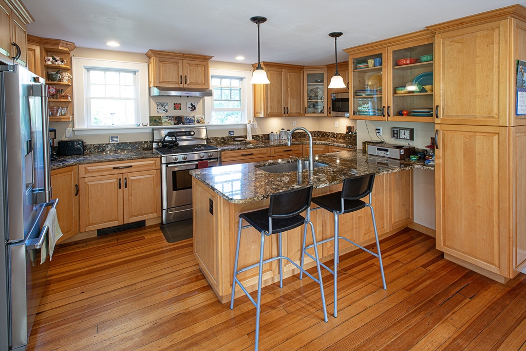 218 Elm Street Northampton, MA 01060 - Photo 12 of 42 a kitchen with stainless steel appliances kitchen island granite countertop wooden floors and white cabinets