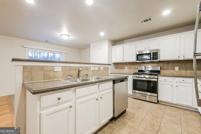 a kitchen with granite countertop white cabinets and stainless steel appliances