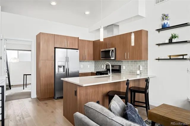 a kitchen with stainless steel appliances a refrigerator a stove a sink a dining table and chairs