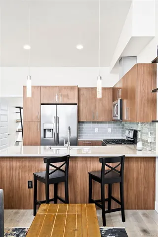 a kitchen with stainless steel appliances granite countertop a table chairs sink and cabinets