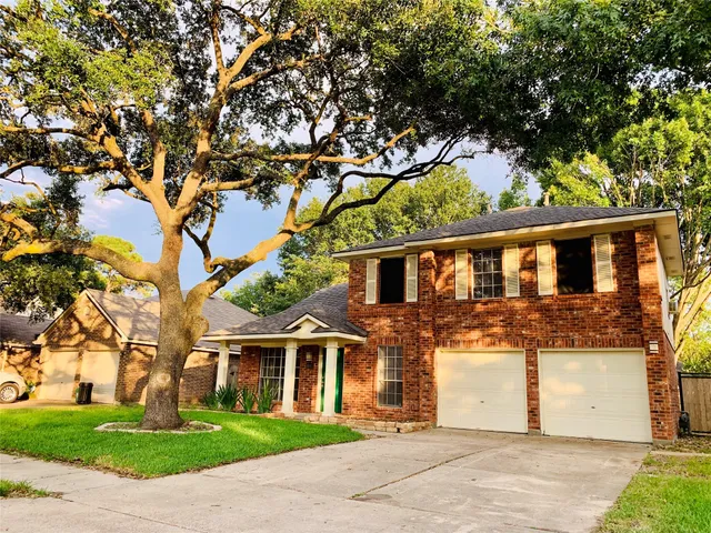 a front view of a house with a garden and tree