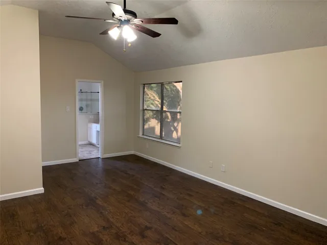 a view of an empty room with window and wooden floor