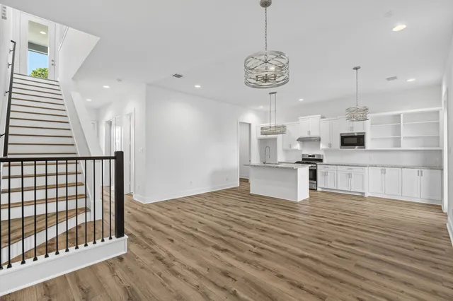 a view of kitchen with stainless steel appliances granite countertop stove oven and white cabinets with wooden floor