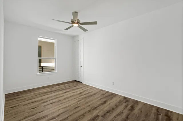 an empty room with wooden floor and ceiling fan