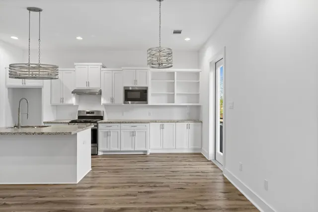 a kitchen with stainless steel appliances granite countertop a sink a stove and a wooden floors