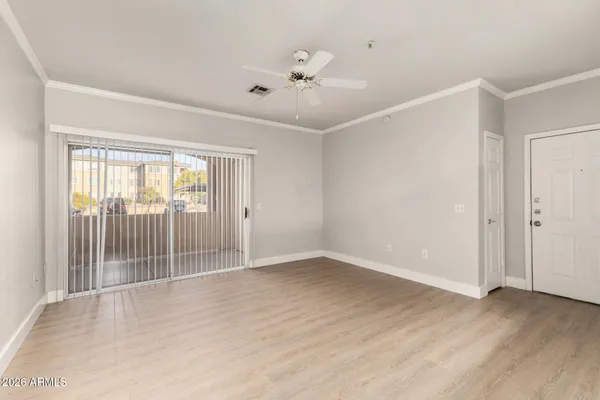 an empty room with wooden floor and ceiling fan