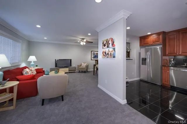 a living room with furniture a flat screen tv and a refrigerator