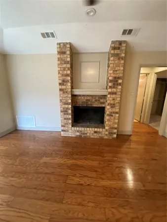 a view of empty room with fireplace and wooden floor