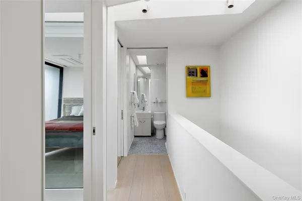 a view of a hallway with wooden floor and a bathroom