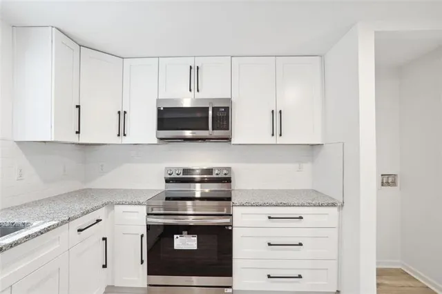 a kitchen with stainless steel appliances white cabinets and a stove a oven with white countertops