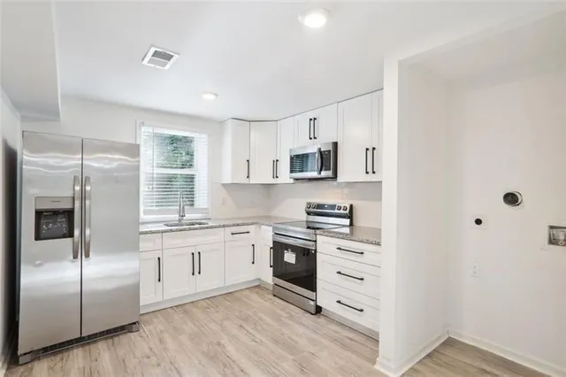 a kitchen with cabinets stainless steel appliances a sink and a window