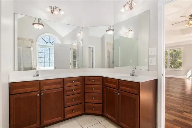 a spacious bathroom with a granite countertop double vanity sink a mirror and a bathtub