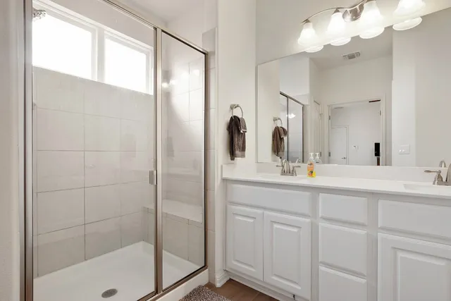 a bathroom with a double vanity sink mirror and shower